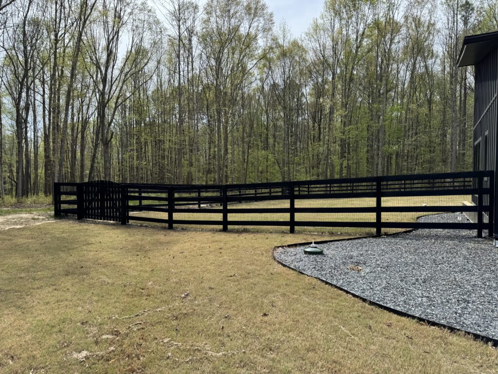 Black four-board ranch fence along a gravel drive