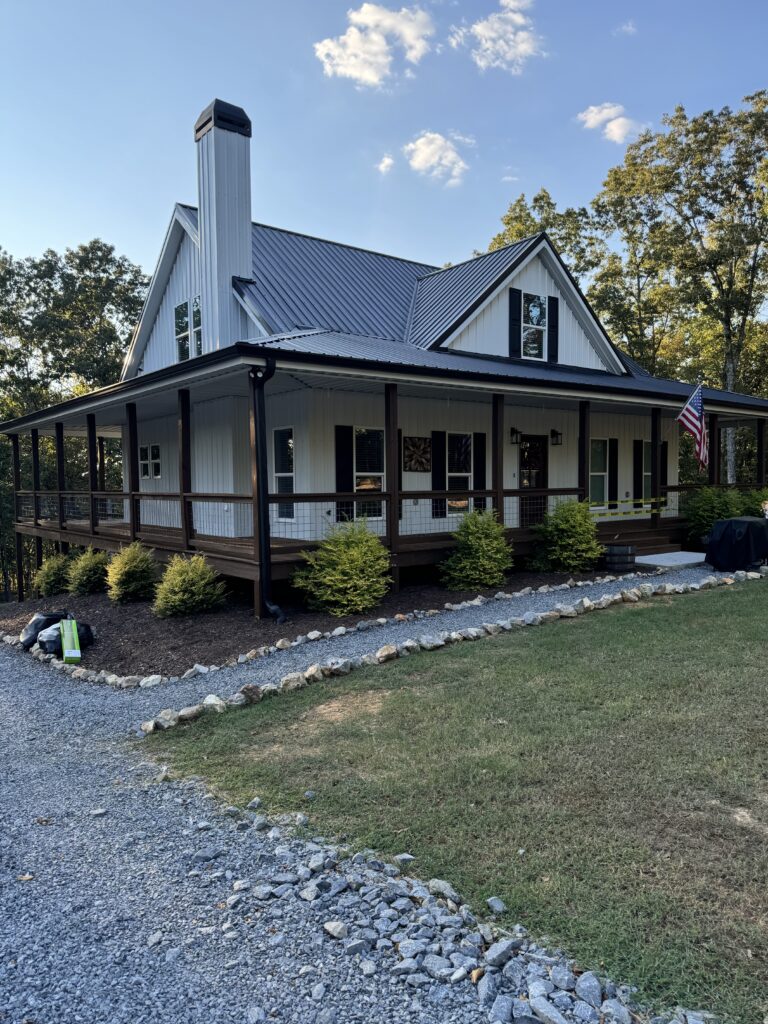 White farmhouse with metal roof and gutters