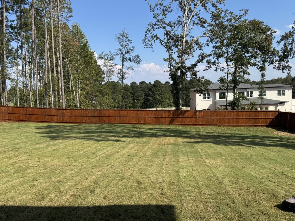 Stained wood privacy fence along a backyard lawn